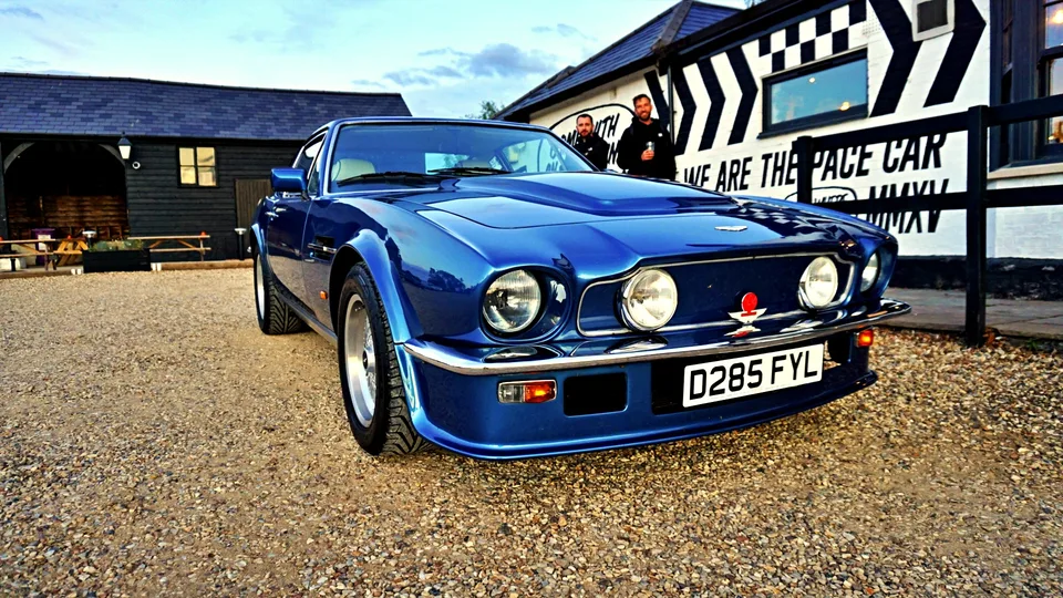 Blue classic Aston Martin outside a motoring venue